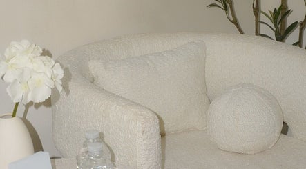 Sofá blanco acogedor en Luarey Beauty Club, Ciudad Obregón, Sonora, MX, rodeado de flores blancas.
