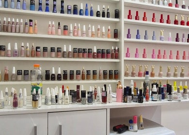 Variedade de esmaltes no Studio de Unhas em Bauru, São Paulo, BR. Mostra cores vibrantes em prateleiras organizadas.
