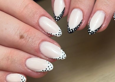Stylish white and black dotted nails at AdoreByChlo in Rugby, England, GB, showcasing creative nail art.