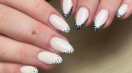 Stylish white and black dotted nails at AdoreByChlo in Rugby, England, GB, showcasing creative nail art.