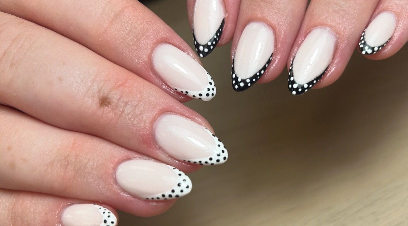 Stylish white and black dotted nails at AdoreByChlo in Rugby, England, GB, showcasing creative nail art.
