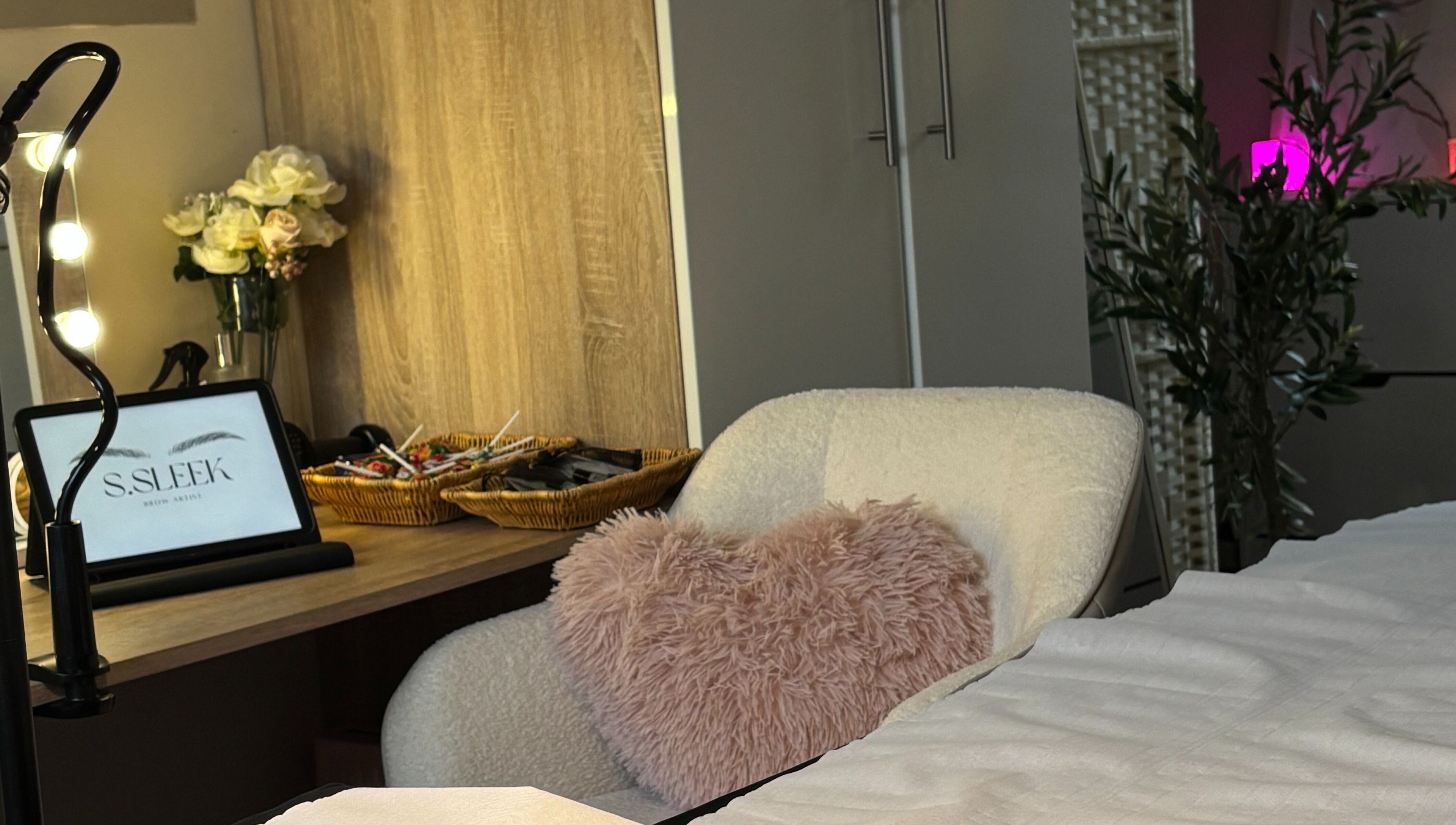 Warm, inviting treatment space at S.Sleek, Bolton, England, GB with a plush chair and decorative accents.