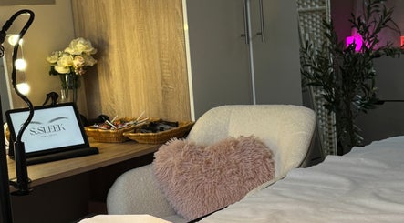 Warm, inviting treatment space at S.Sleek, Bolton, England, GB with a plush chair and decorative accents.