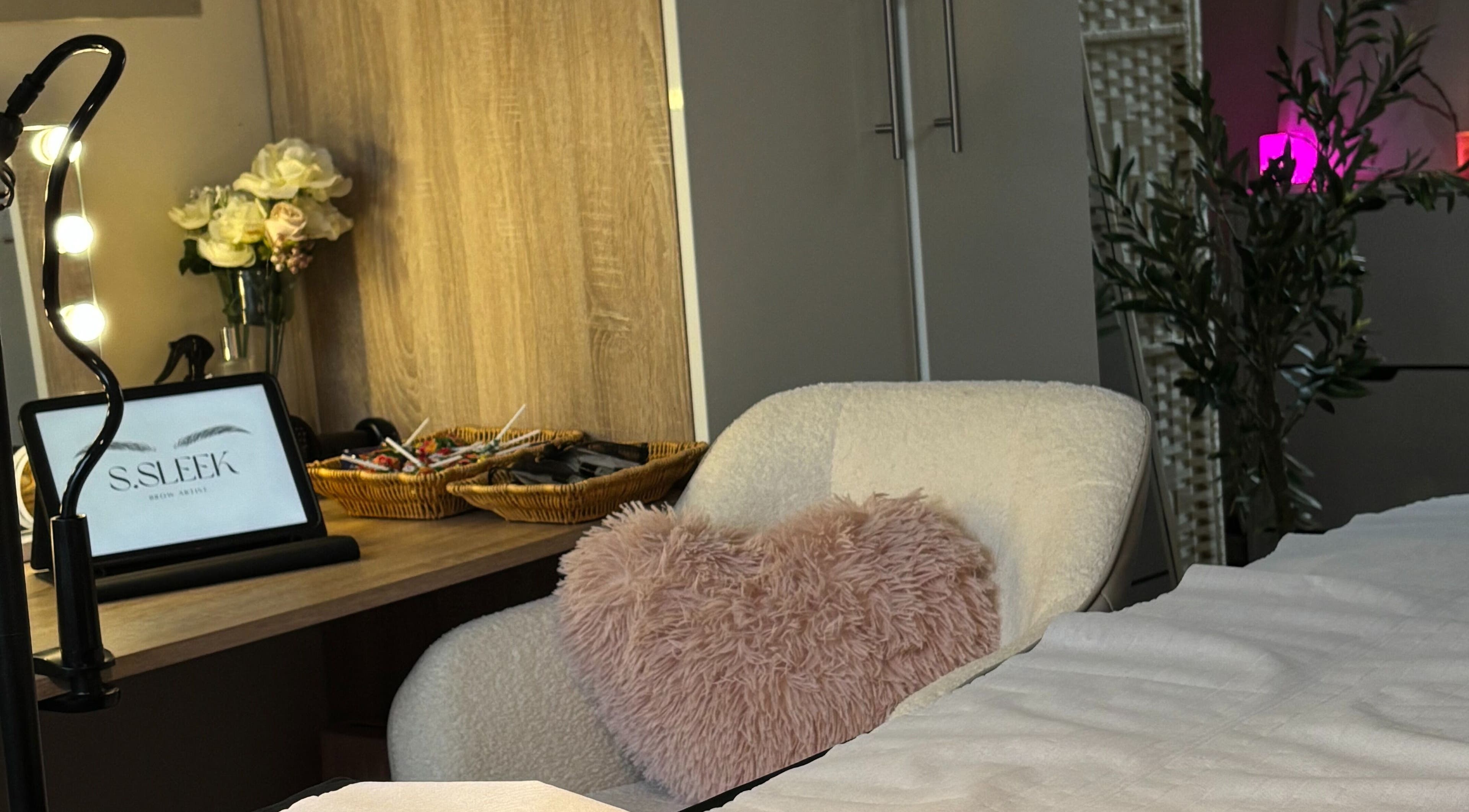 Warm, inviting treatment space at S.Sleek, Bolton, England, GB with a plush chair and decorative accents.