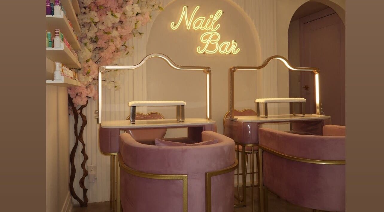 Elegant nail bar seating at Maison Belissy, Toronto, Ontario, CA with pink velvet chairs and floral decor.