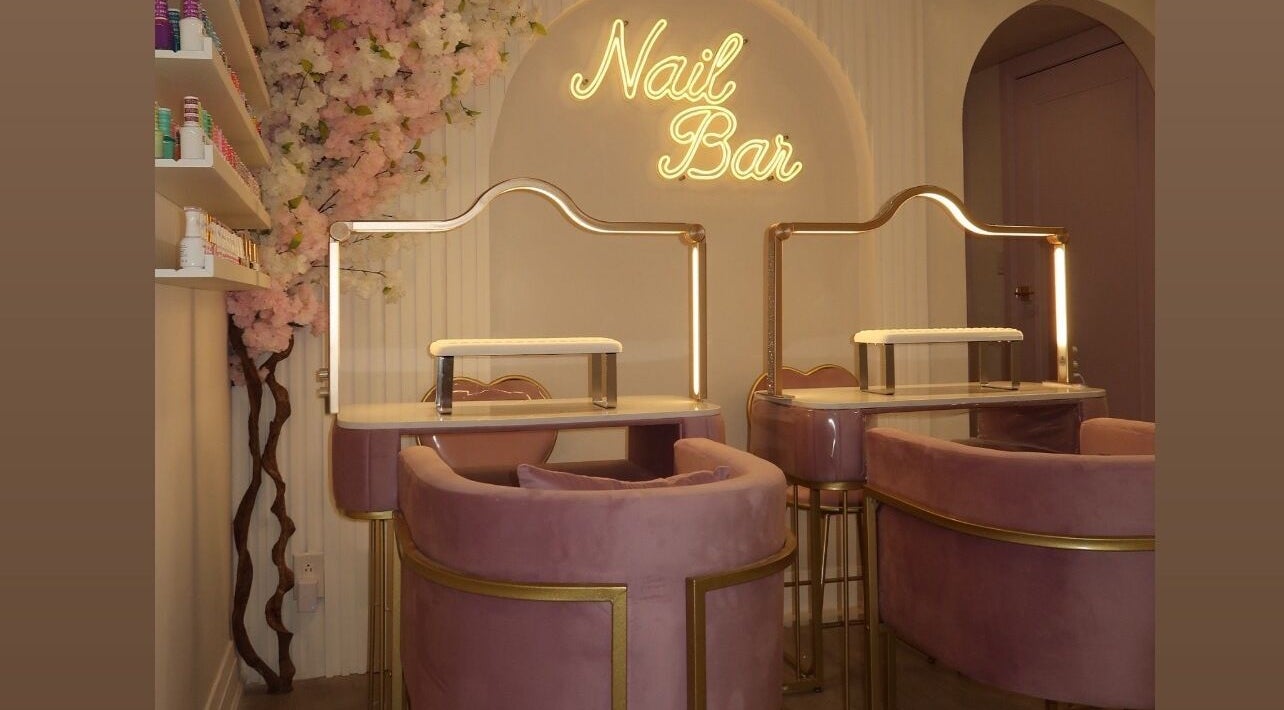 Elegant nail bar seating at Maison Belissy, Toronto, Ontario, CA with pink velvet chairs and floral decor.