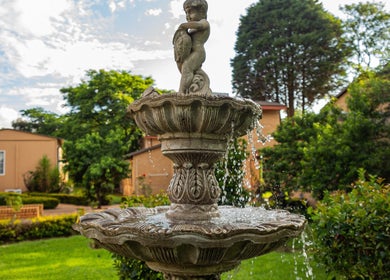 Elegant garden fountain at Wisani Spa, Chartwell, Gauteng, ZA, surrounded by lush greenery.