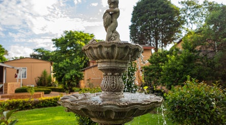 Elegant garden fountain at Wisani Spa, Chartwell, Gauteng, ZA, surrounded by lush greenery.