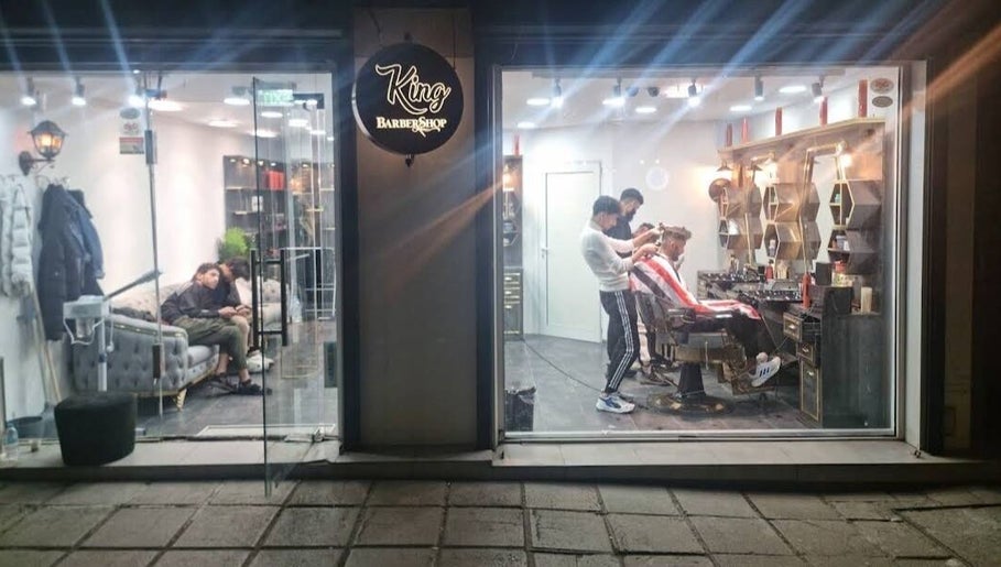 حلاق يعمل على قص شعر زبون في King BarBer Shop في صوفيا، صوفيا سيتي، BG.