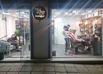 حلاق يعمل على قص شعر زبون في King BarBer Shop في صوفيا، صوفيا سيتي، BG.