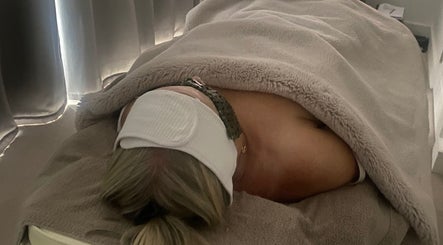 Relaxed client under warm blanket at Body & Face spa in Ashford, England, GB enjoying soothing treatment.