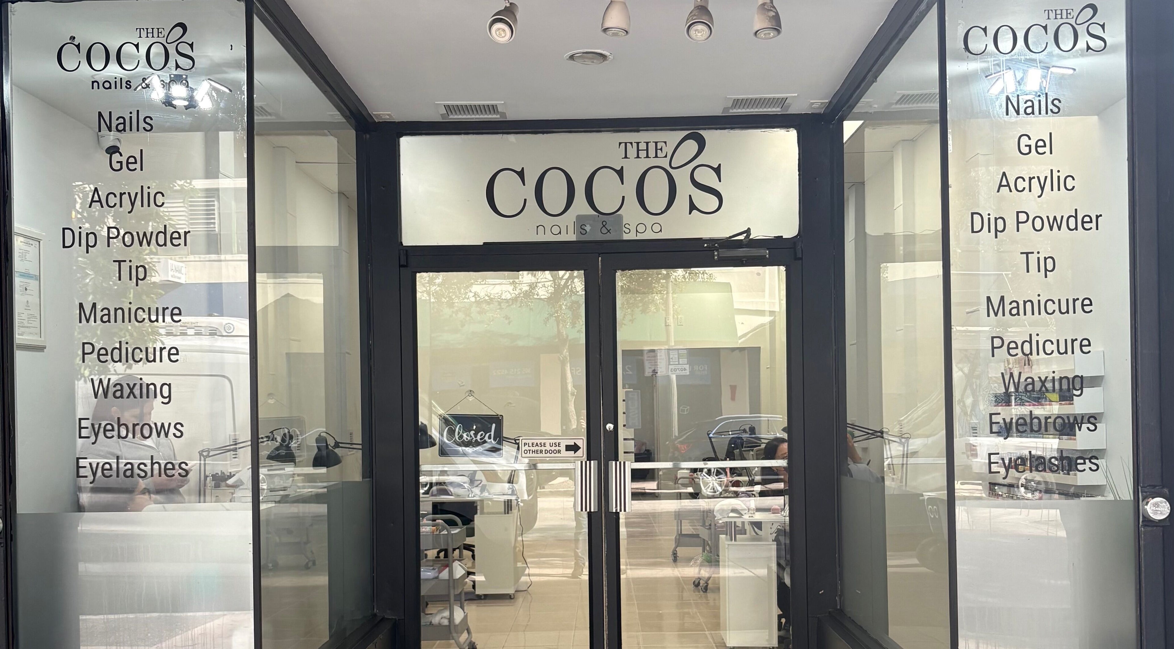 Entrance of The Coco's Nail & Spa in Miami, Florida, US, featuring beauty services list on glass doors.