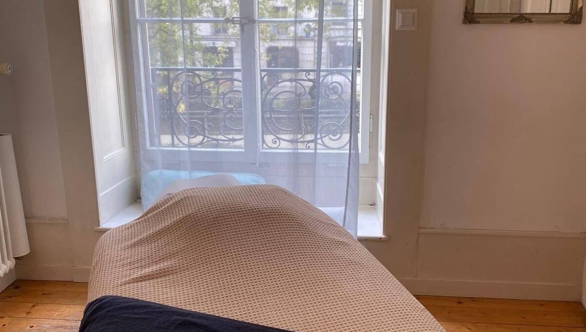 Salle de massage lumineuse chez ART Institut, Genève, Genève, CH avec lit confortable et fenêtre ensoleillée.