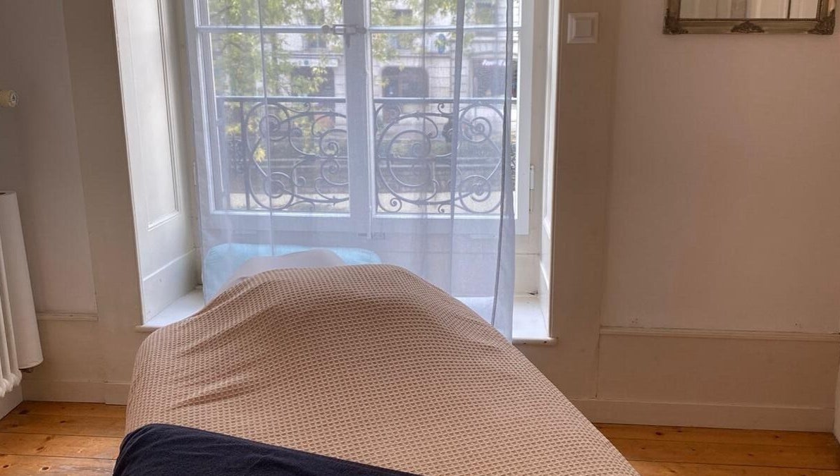 Salle de massage lumineuse chez ART Institut, Genève, Genève, CH avec lit confortable et fenêtre ensoleillée.