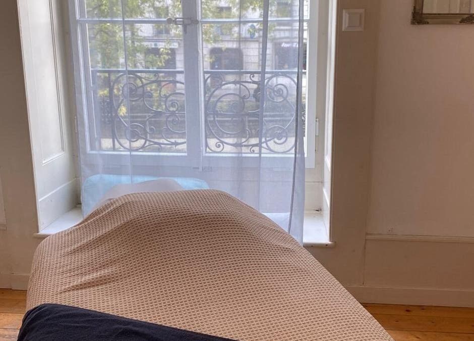 Salle de massage lumineuse chez ART Institut, Genève, Genève, CH avec lit confortable et fenêtre ensoleillée.