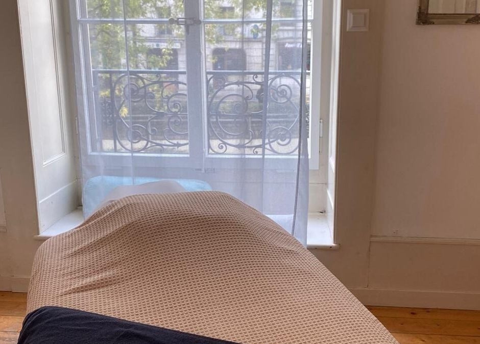 Salle de massage lumineuse chez ART Institut, Genève, Genève, CH avec lit confortable et fenêtre ensoleillée.