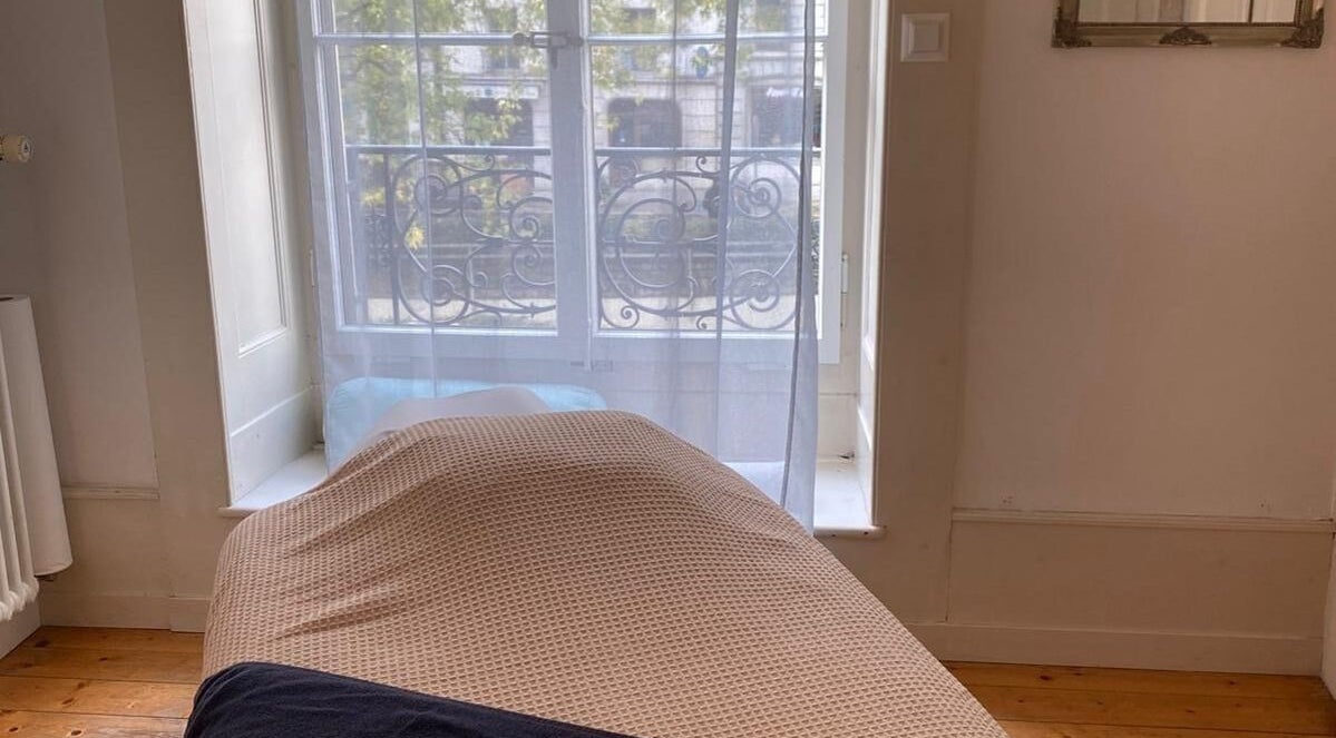 Salle de massage lumineuse chez ART Institut, Genève, Genève, CH avec lit confortable et fenêtre ensoleillée.