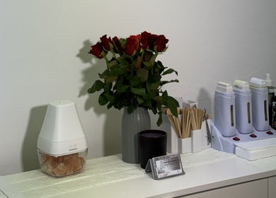 Aesthetic beauty supplies at Sweet Epil Beauty, London, England, GB with a vase of roses and spa tools.