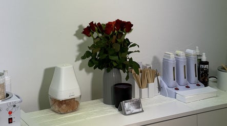Aesthetic beauty supplies at Sweet Epil Beauty, London, England, GB with a vase of roses and spa tools.