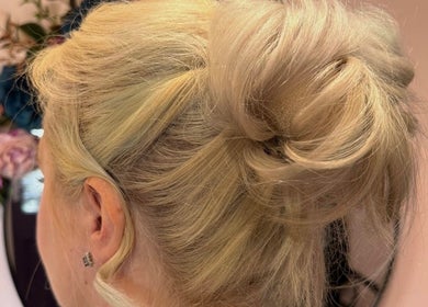 Elegant blonde updo hairstyle at Poppy’s Make Up & Beauty Bar, Redditch, England, GB, with floral decor backdrop.