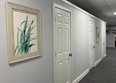 Peaceful hallway at Breezy Massage Spa in Sarasota, Florida, US, with calming wall art and white doors.