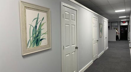 Peaceful hallway at Breezy Massage Spa in Sarasota, Florida, US, with calming wall art and white doors.
