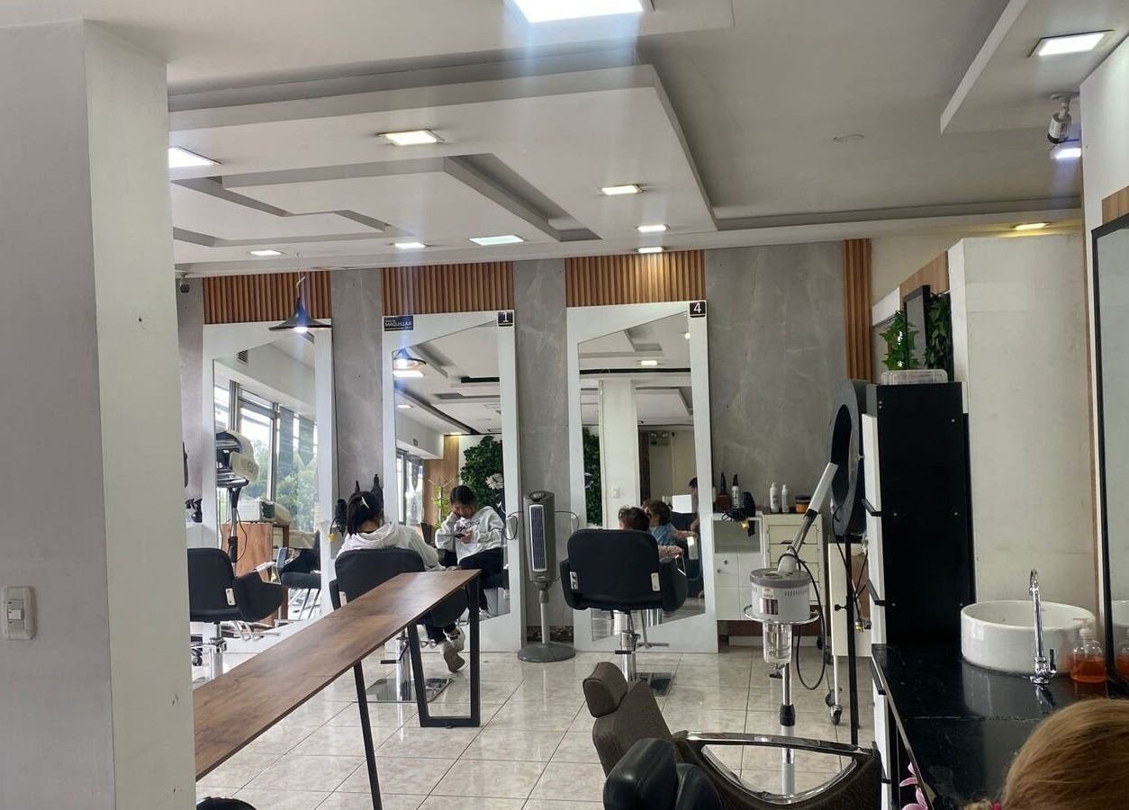 Interior moderno de Blondin Studio en Quito, Pichincha, EC, con estaciones de belleza iluminadas.