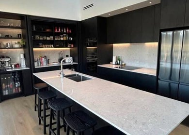Sleek kitchen design at Bless The Mess Cleaning Co., Wānaka, Otago Region, NZ, featuring black cabinets and an island.