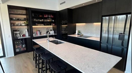 Sleek kitchen design at Bless The Mess Cleaning Co., Wānaka, Otago Region, NZ, featuring black cabinets and an island.