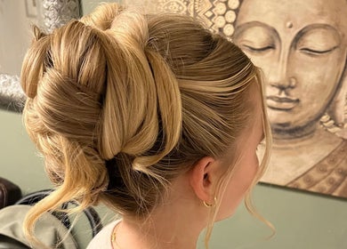 Blonde hair styled in a chic updo at Bylucydomeneghetti, Durham, England, GB near a serene Buddha painting.