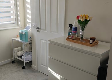 Relaksacyjny kącik w MK Beauty, Hartlepool, Anglia, GB z wazonem tulipanów na białej komodzie.