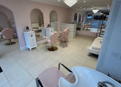 Chic salon interior at Rose Gold hair & beauty, Hounslow, England, GB, featuring plush pink chairs and mirrors.