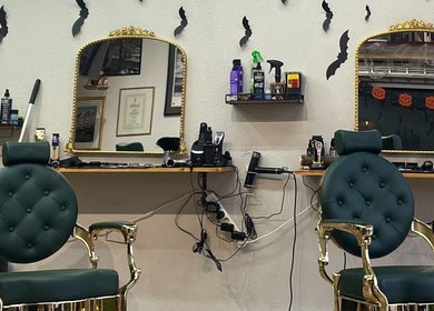 Stilfuldt interiør hos The Royal Salon, Søborg, DK, med grønne stole og gyldne spejle.