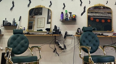 Stilfuldt interiør hos The Royal Salon, Søborg, DK, med grønne stole og gyldne spejle.