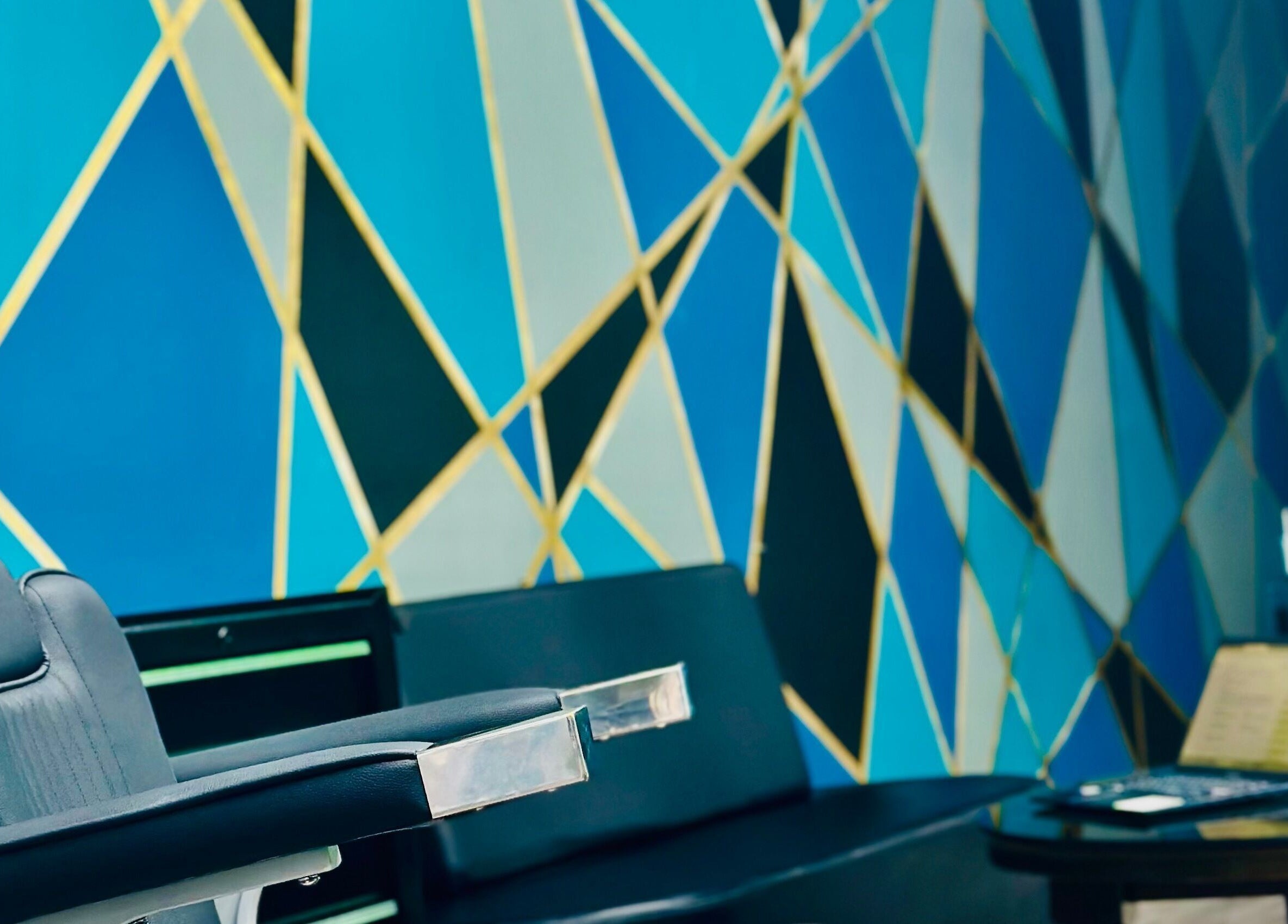 Interior de ELITE BARBER CLUB en Willemstad, Curaçao, CW con silla moderna y mural geométrico.