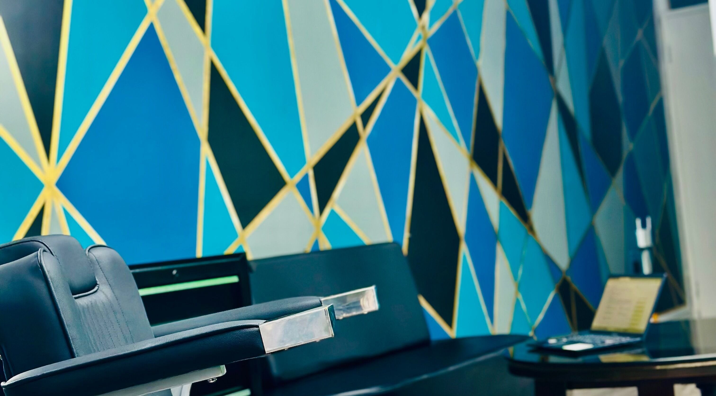 Interior de ELITE BARBER CLUB en Willemstad, Curaçao, CW con silla moderna y mural geométrico.