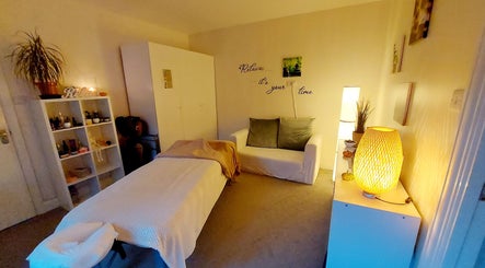 A tranquil massage room in Harmony Wellbeing, Croydon, England, GB, with warm lighting and soothing decor.