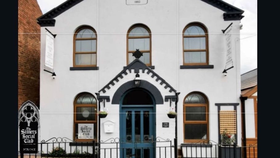 Front view of The Sinners Social Club, a historic venue in Ilkeston, England, GB with arched windows and blue door.
