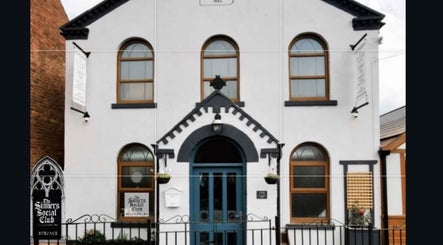Front view of The Sinners Social Club, a historic venue in Ilkeston, England, GB with arched windows and blue door.