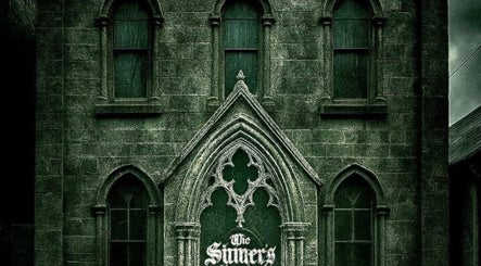 Gothic facade of The Sinners Social Club in Ilkeston, England, GB, showcasing arched windows and stone details.