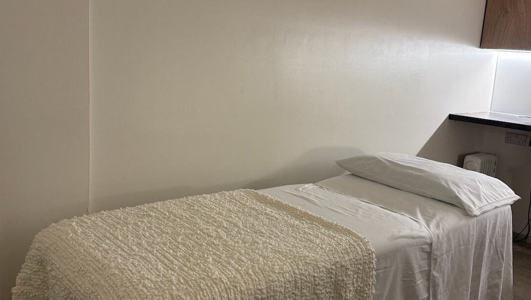 Cozy massage room at Contourista London in London, England, GB with a softly lit bed and warm decor.