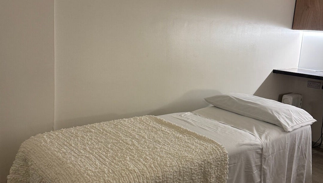 Cozy massage room at Contourista London in London, England, GB with a softly lit bed and warm decor.
