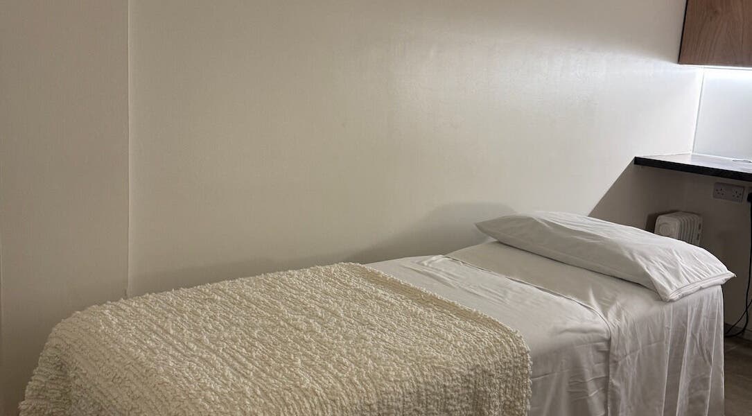 Cozy massage room at Contourista London in London, England, GB with a softly lit bed and warm decor.