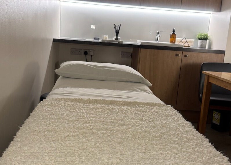 Cozy treatment room at Contourista London in London, England, GB with bed, table, and decor.