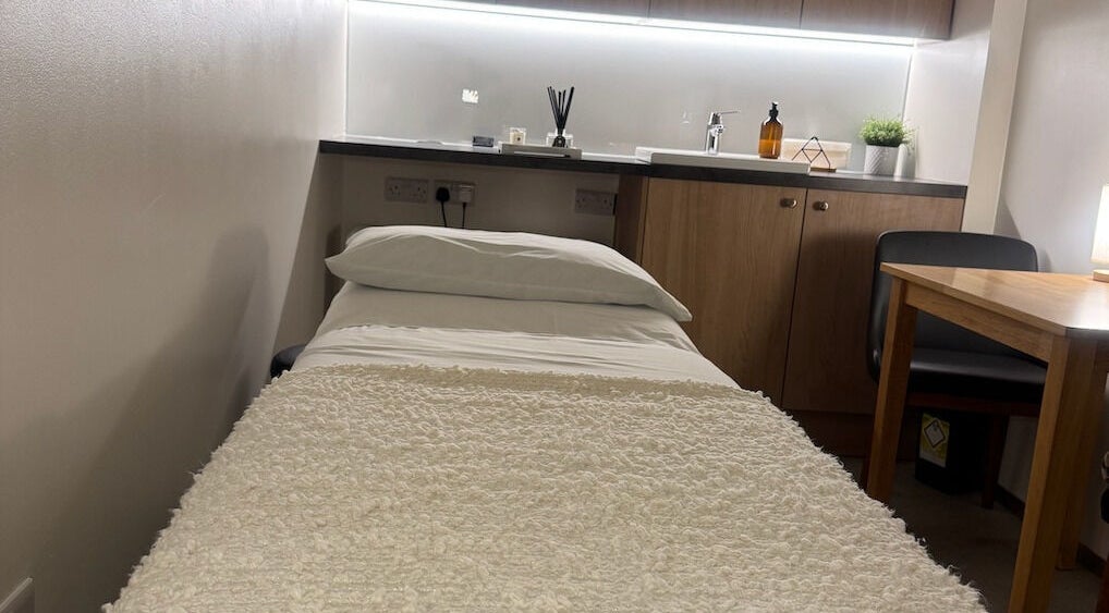 Cozy treatment room at Contourista London in London, England, GB with bed, table, and decor.