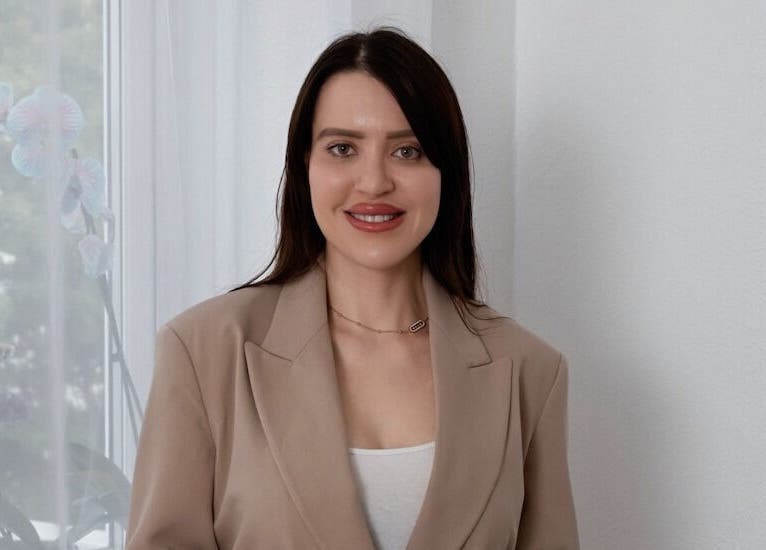 Smiling woman in beige suit at Contourista London, London, England, GB, exuding professionalism and warmth.