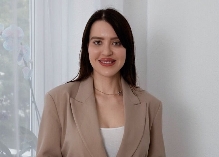 Smiling woman in beige suit at Contourista London, London, England, GB, exuding professionalism and warmth.