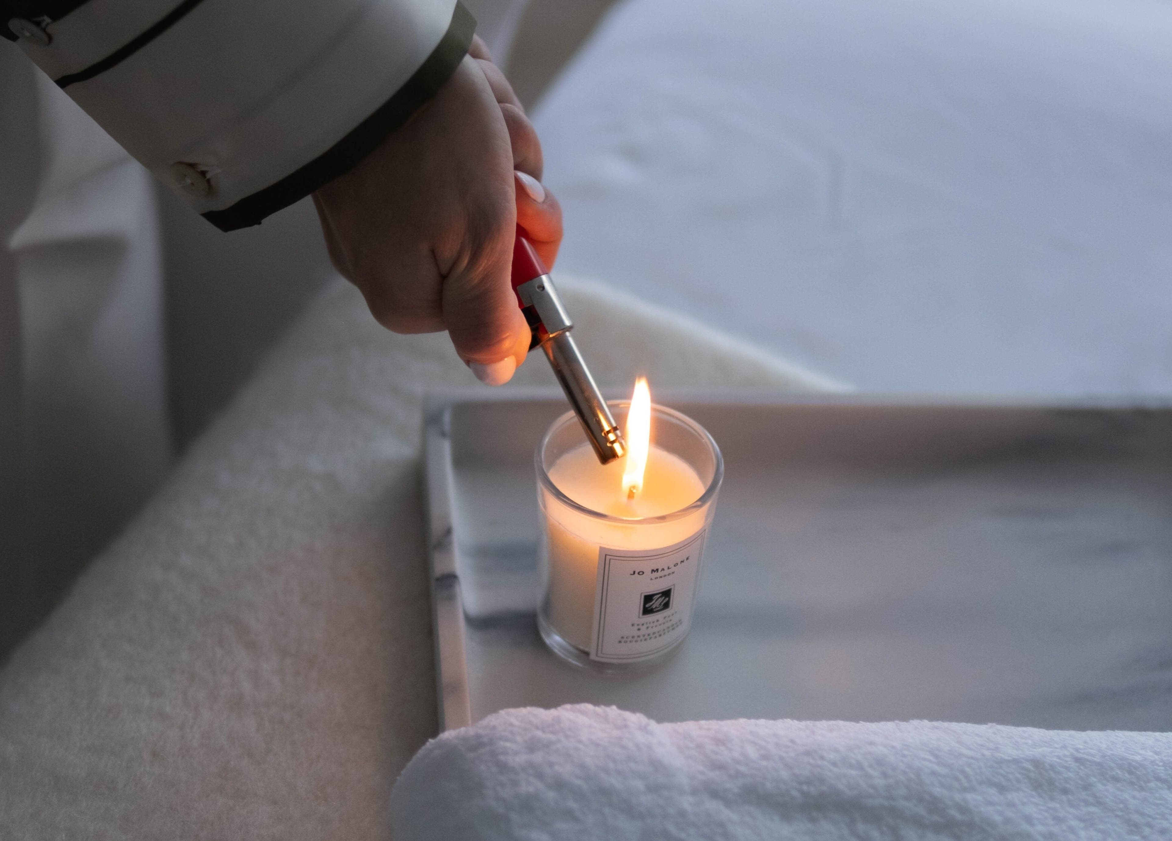 A hand lights a candle in spa room at Contourista London, enhancing relaxation in London, England, GB.