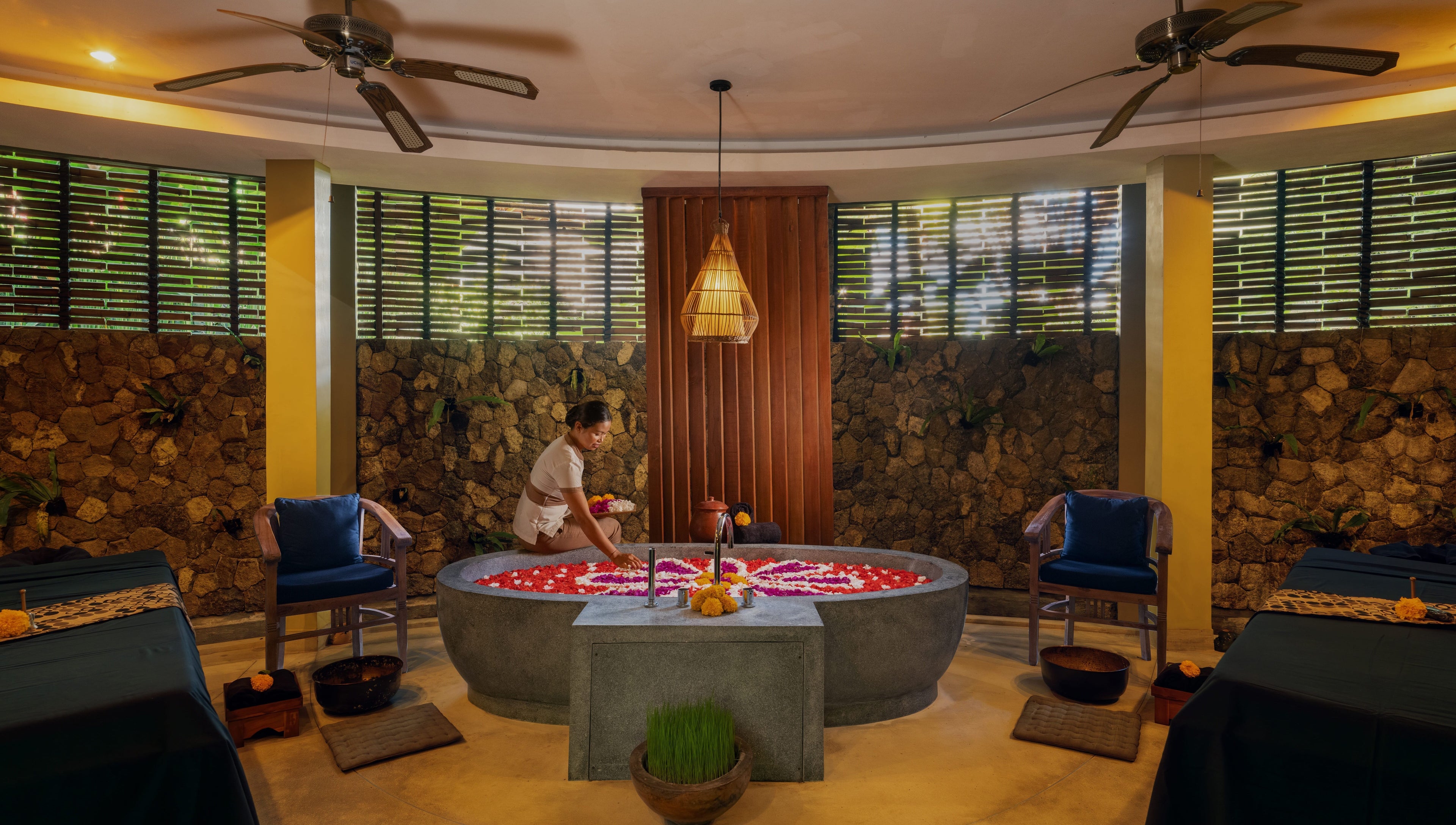 A therapist prepares a floral bath at Darbha Spa Ubud in Bali, Bali, ID, highlighting a serene and relaxing ambiance.