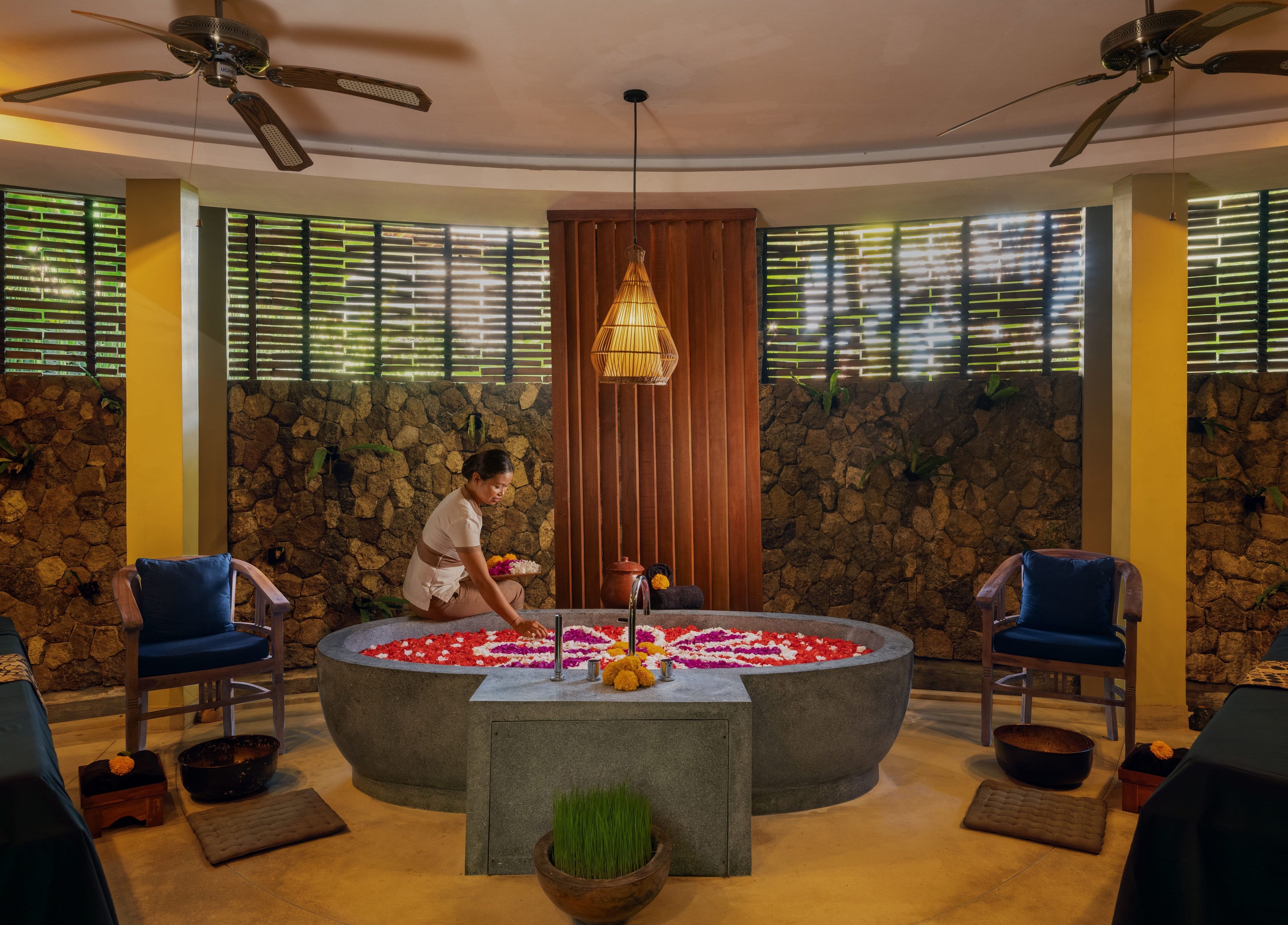A therapist prepares a floral bath at Darbha Spa Ubud in Bali, Bali, ID, highlighting a serene and relaxing ambiance.